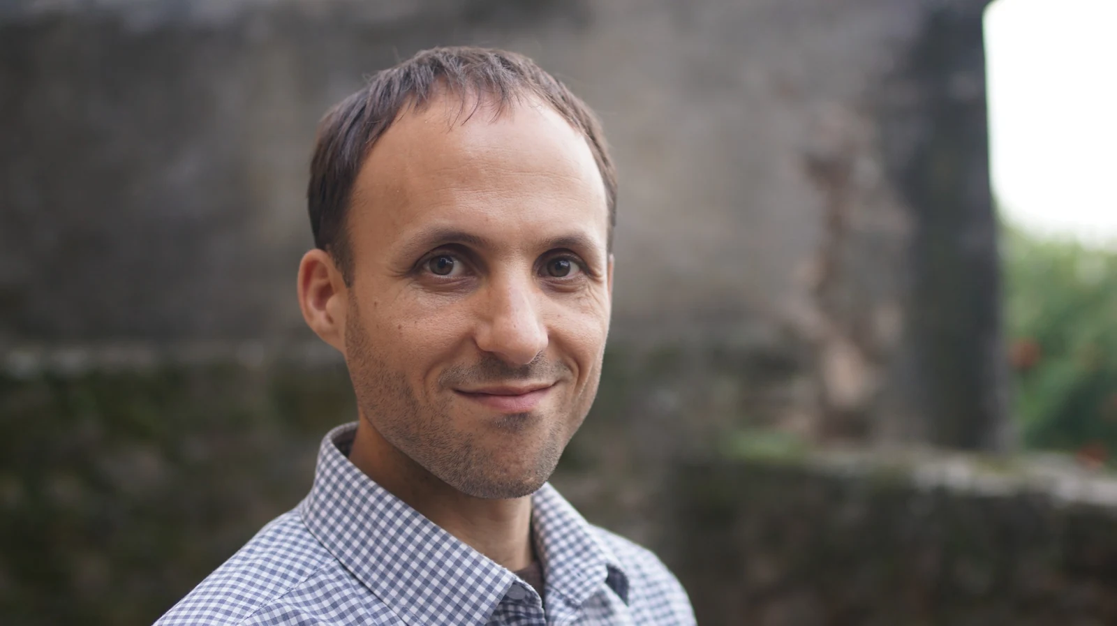 Bharat Berwing outdoors, smiling calmly in a professional portrait.